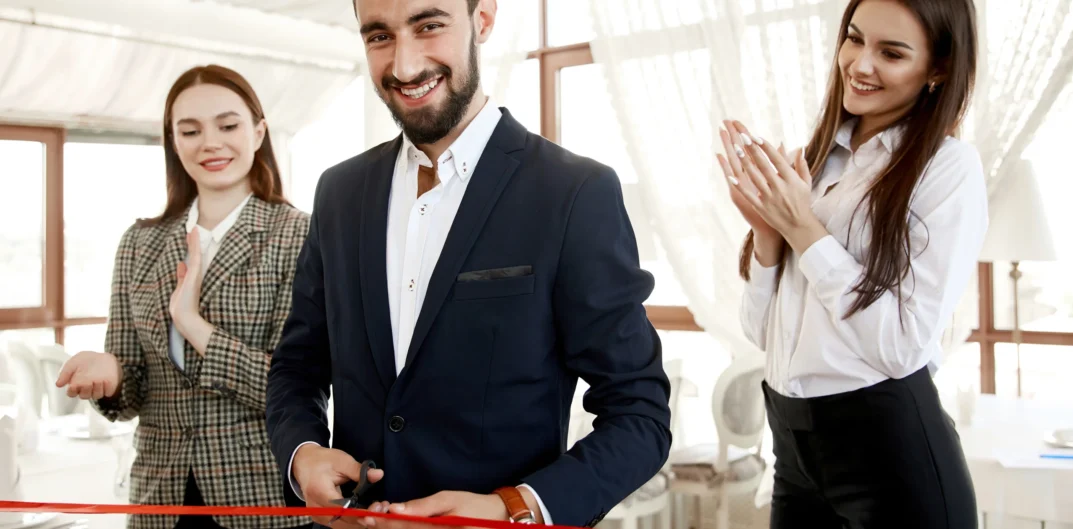 handsome-man-is-cutting-red-ribbon-grand-opening-restaurant-with-two-beautiful-assistants-women