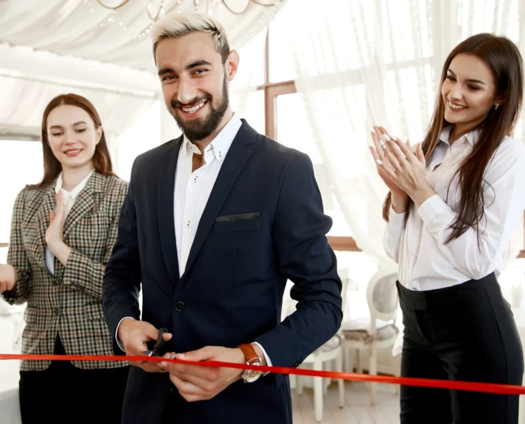 handsome-man-is-cutting-red-ribbon-grand-opening-restaurant-with-two-beautiful-assistants-women