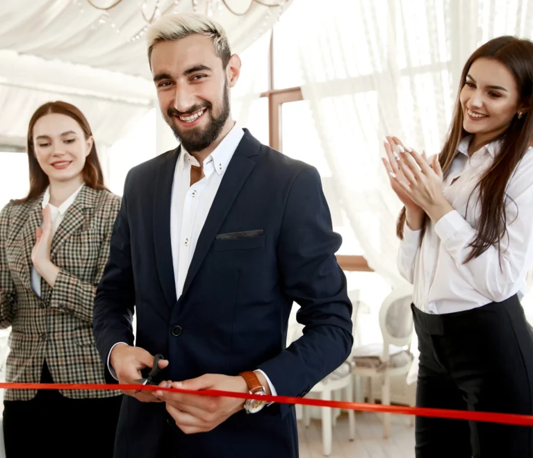 handsome-man-is-cutting-red-ribbon-grand-opening-restaurant-with-two-beautiful-assistants-women